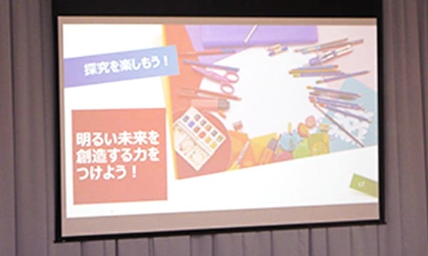 スクリーンに投影されたスライド。「探究を楽しもう!」「明るい未来を創造する力をつけよう!」とある
